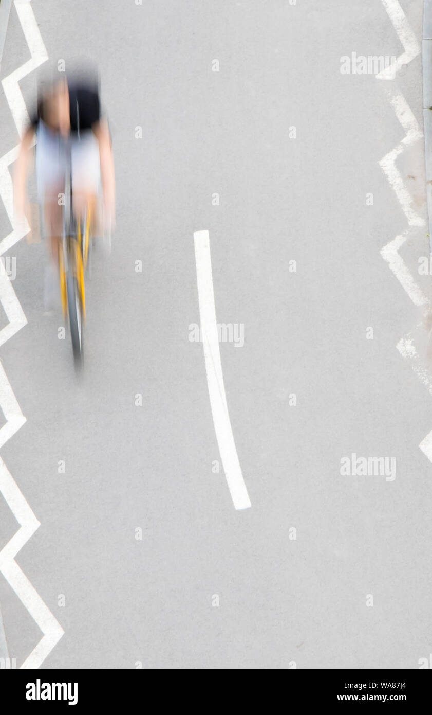 Defocused abstract  motion blur of young man riding a bike on bicycle lane, from above Stock Photo