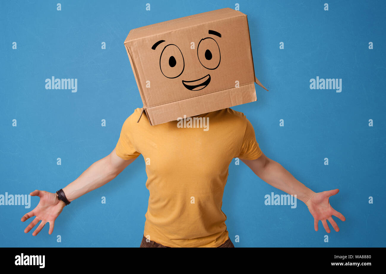 Young man standing and gesturing with a cardboard box on his head with ...
