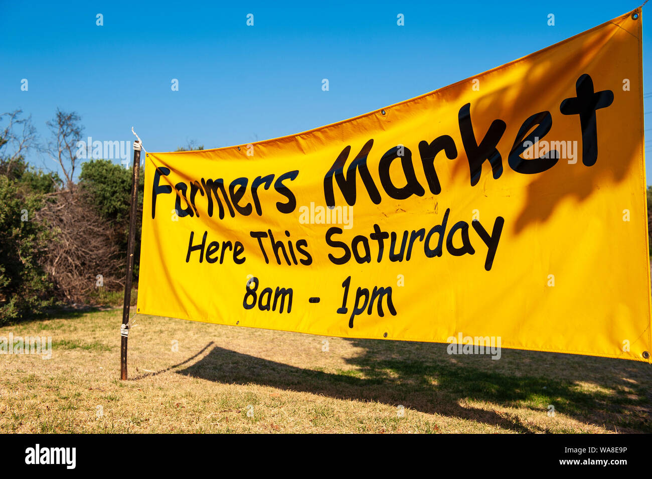 Sign for farmers market on Saturday on bright yellow background with blue sky, Australia Stock Photo