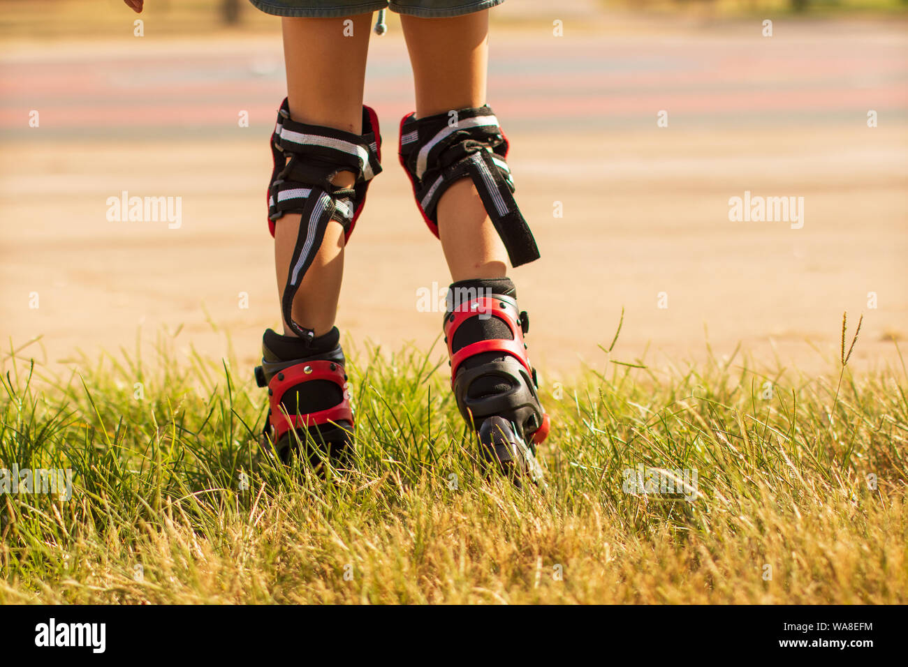 child learns to ride roller skates, children's legs in roller skates and knee-lengths from the back Stock Photo