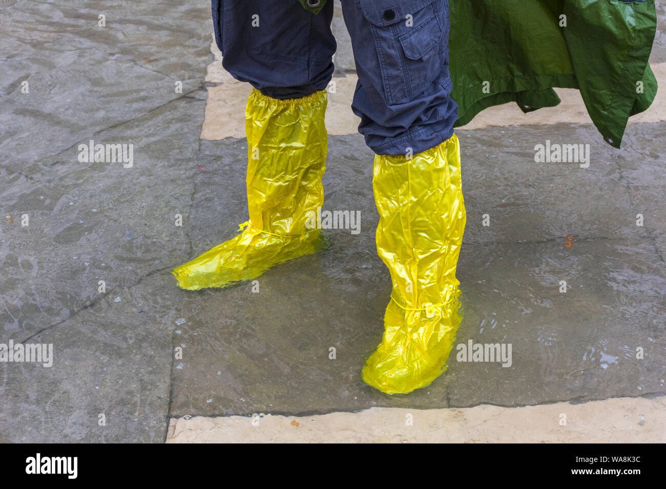 A man wearing Goldon stivali waterproof overshoes during an Acqua alta (high water) event, Saint Mark's Square, Venice, Italy Stock Photo