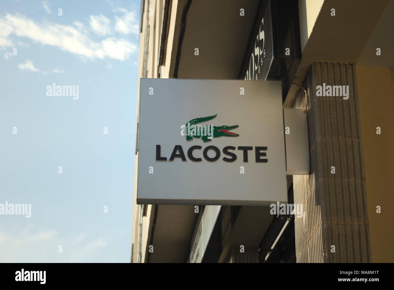 Store sign of lacoste logo on an old building's facade in Spain Stock Photo