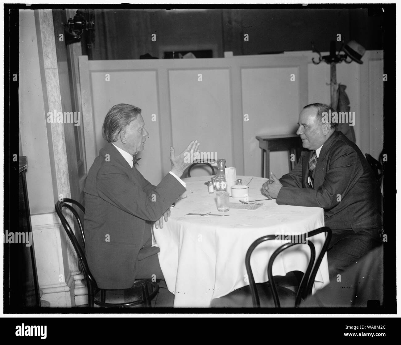 Capitol lunch for two. Washington, D.C., Dec. 21. Party lines are forgotten when members of the United States Senate [...] the Capitol Restaurant for luncheon. The diner is the favorite spot right now the as the Senators return for the coming session [...] Here we see the Republican Senator William E. Borah of Idaho, Driving home a point in a discussion [with] Senator Bennett Champ Clark, of Missouri, as [...] listens Stock Photo
