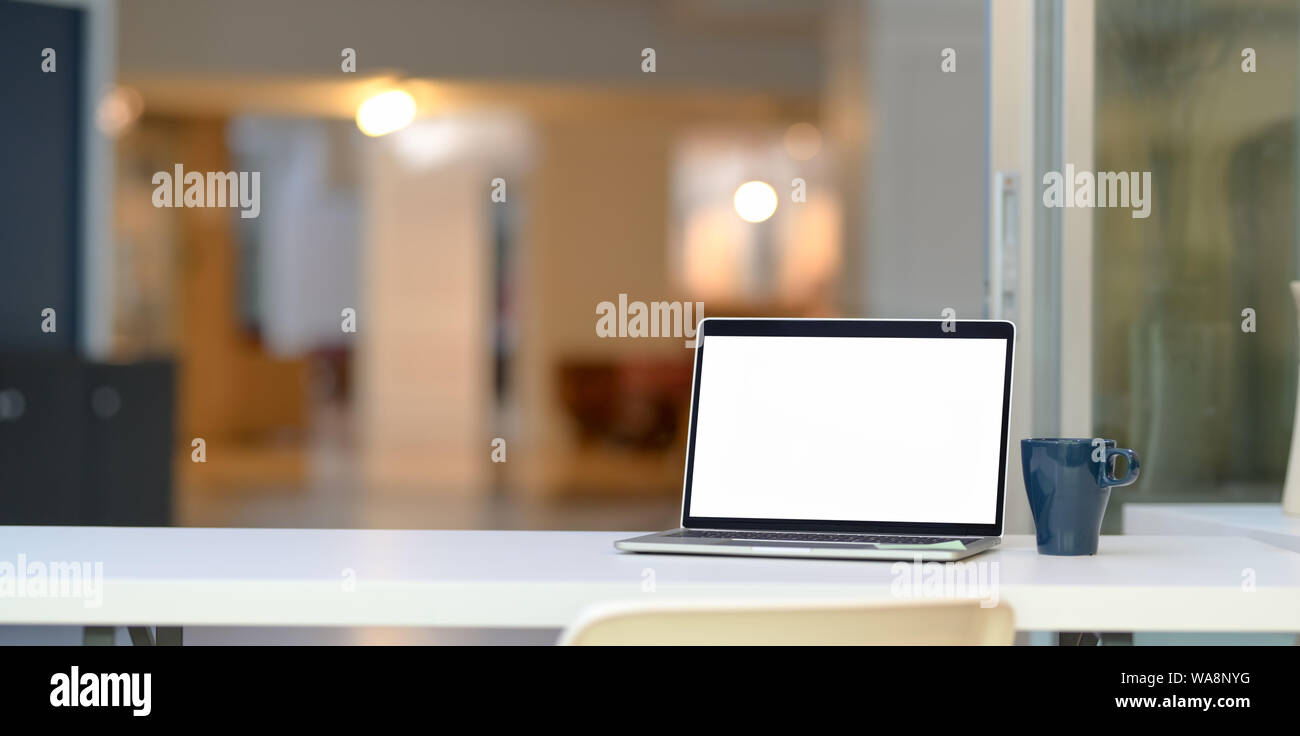 Open blank screen laptop computer and coffee cup in modern office style ...