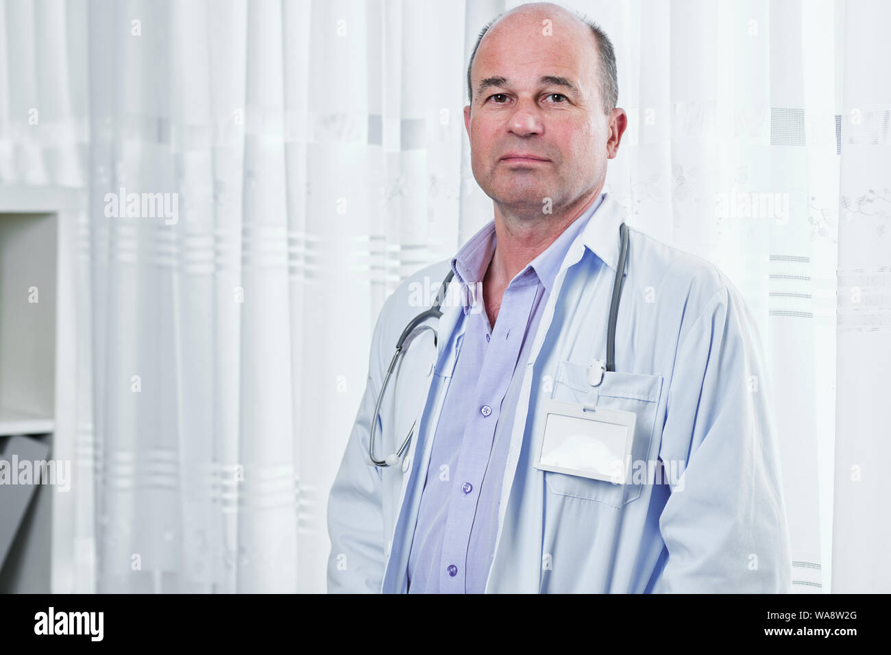 Portrait of sad serious doctor in white labcoat with empty badge looking at camera Stock Photo