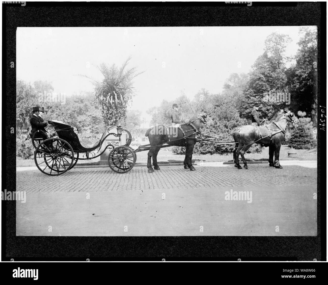 Carriage, drawn by four horses, with drivers & footmen, in front of garden Stock Photo