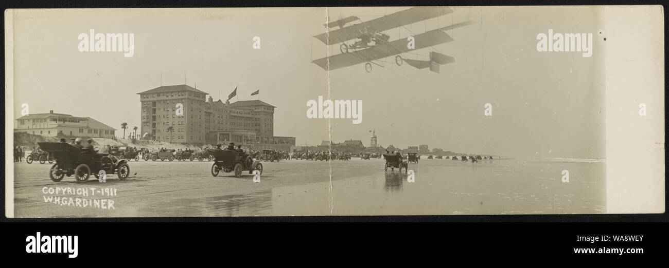 Cars on beach with airplane overhead and Clarendon Hotel in background ...