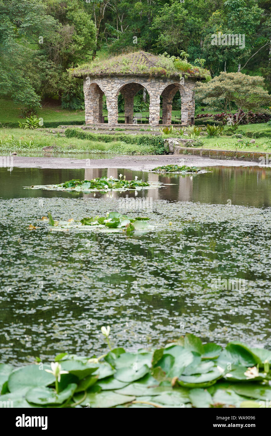 Stone arbor next to lake in green park background Stock Photo