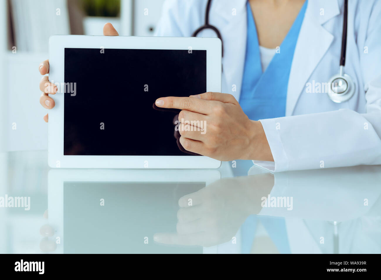Female doctor using tablet computer while sitting at the workplace ...