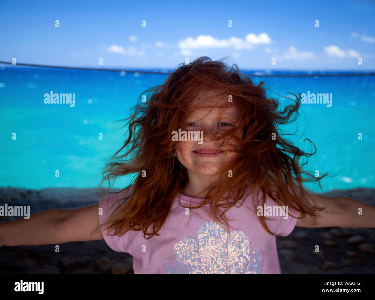 A young red headed girl in Crete with her hair blowing in the wind. Stock Photo