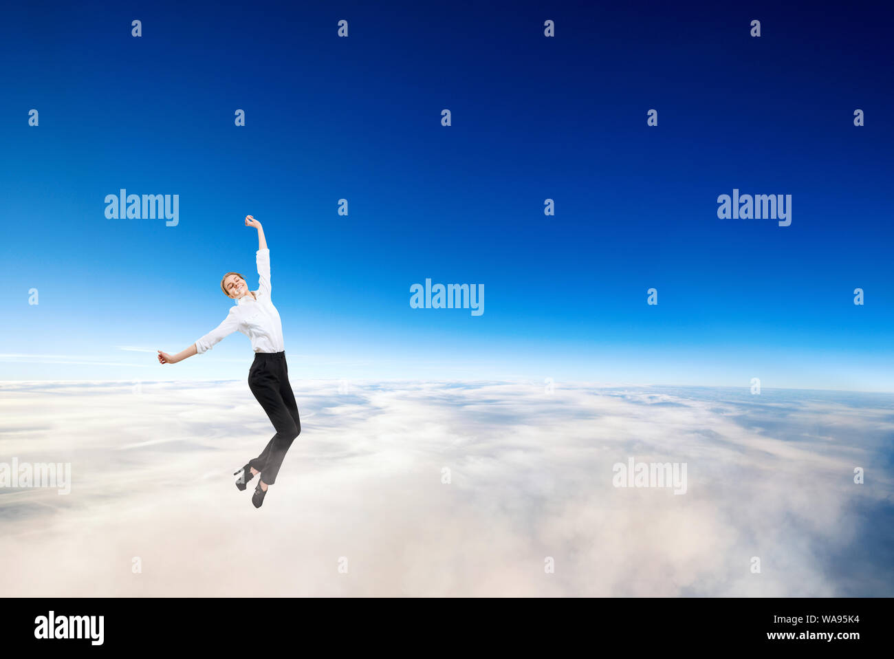Young businesswoman in formal wear flying in blue sky. Stock Photo