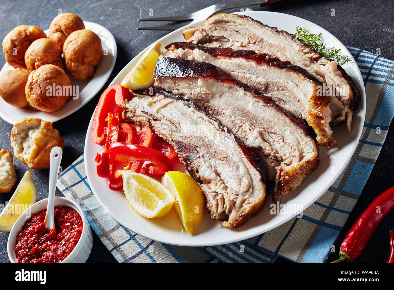 jerky pork belly cut in slices on a white plate on a concrete table