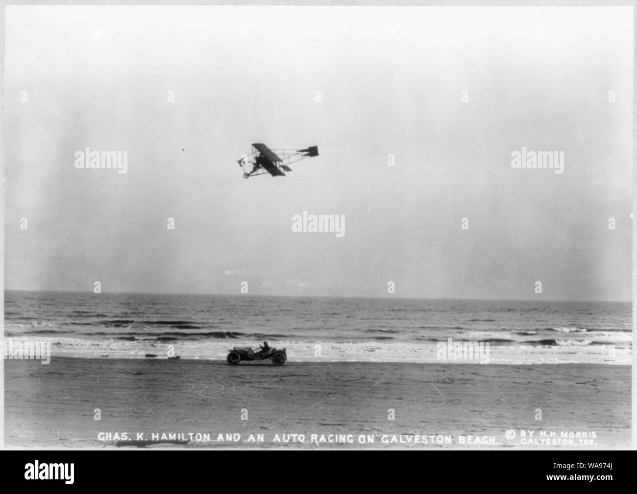 Charles K. Hamilton, in biplane, racing an auto on Galveston beach Stock Photo
