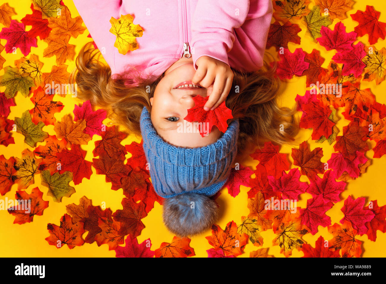 Top view of a happy child lying on the autumn leaves. Stock Photo