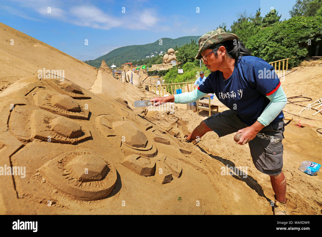 Chinese workers carve sand sculptures featuring shape of cartoon ...