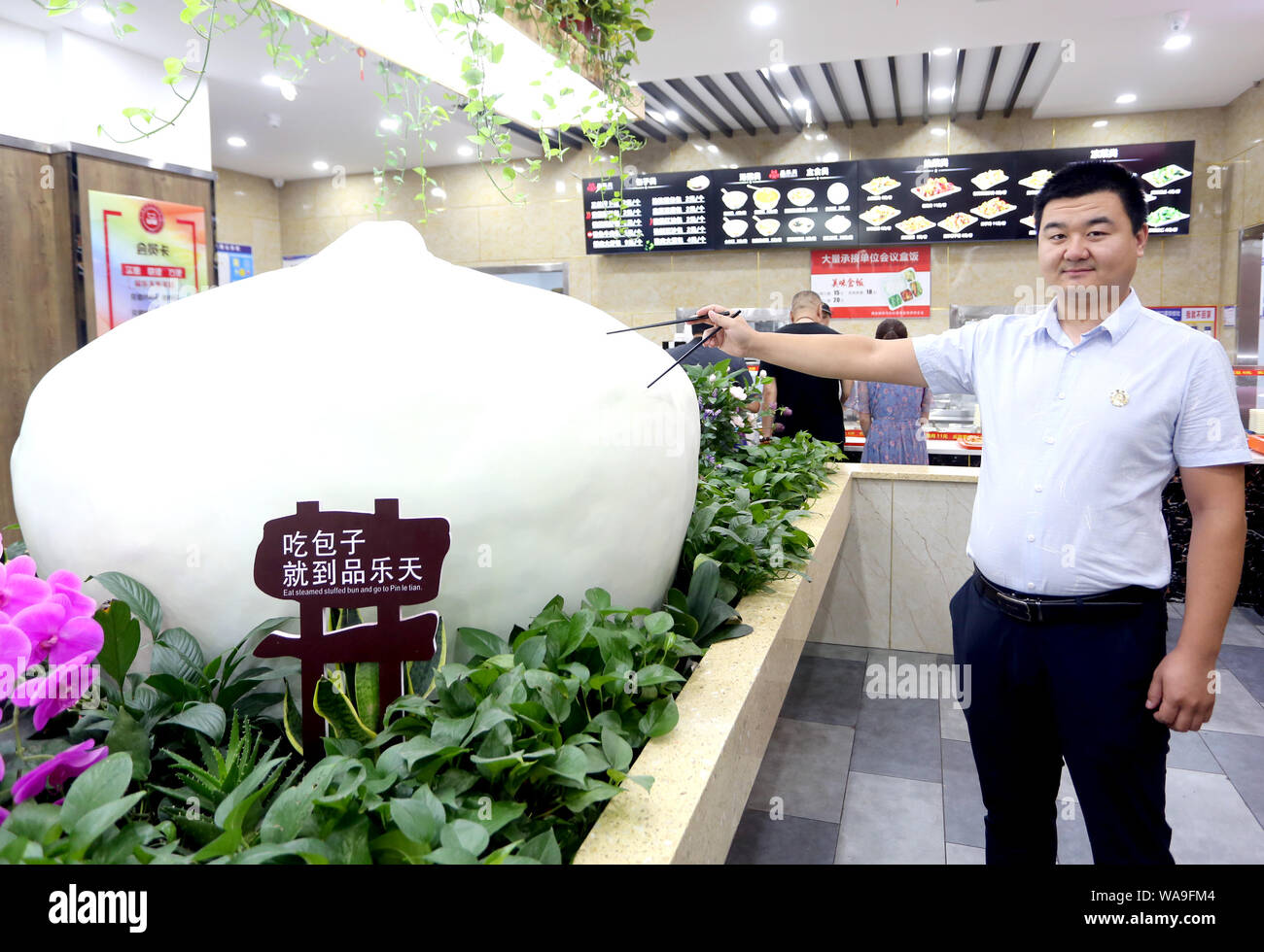 Customers pose for photos with a huge 'Steamed Stuffed Bun', which is 1.5 meters in diameter, at a breakfast restaurant in Xi'an city, northwest China Stock Photo