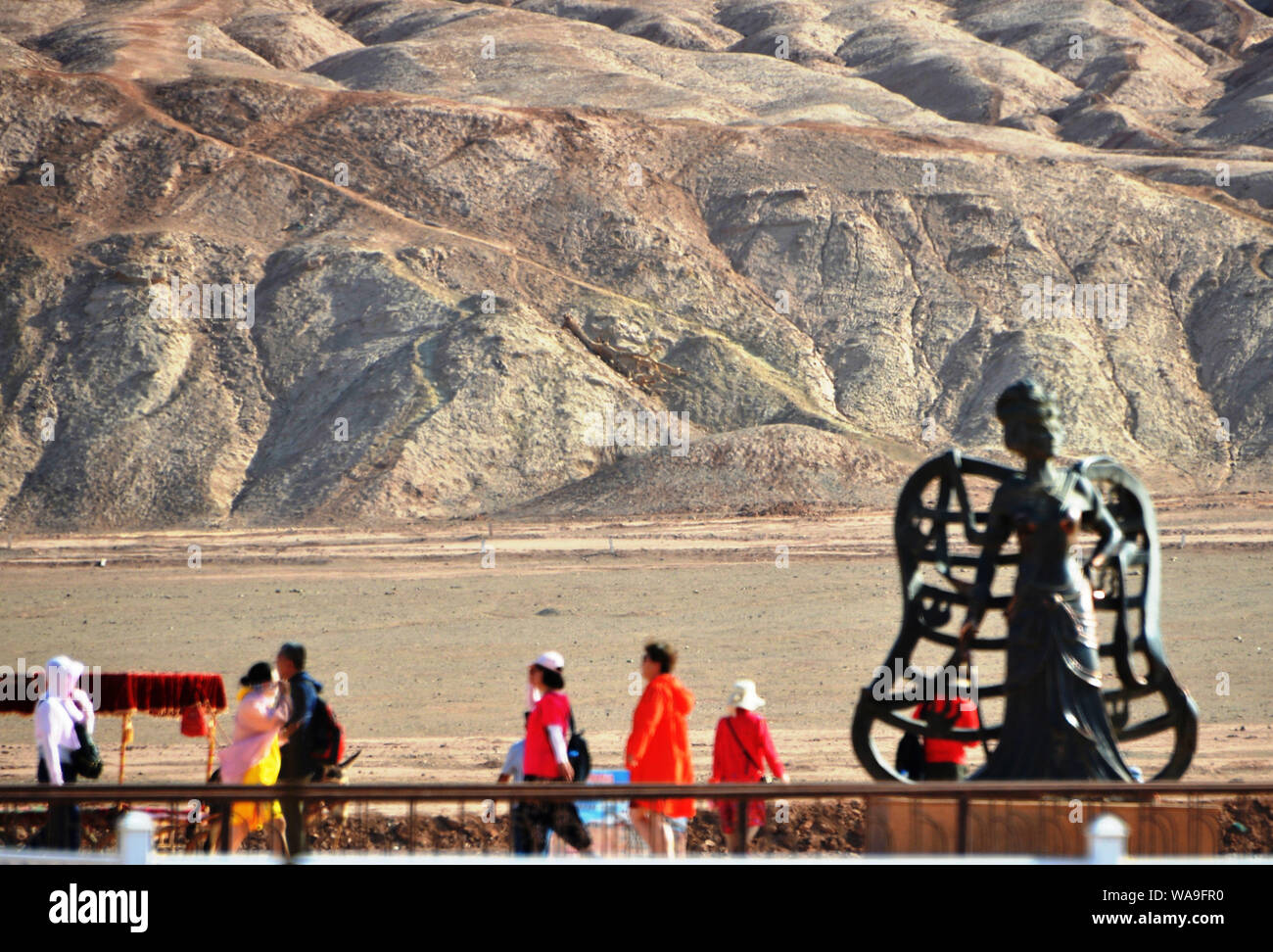 Tourists pose for photos with the landmark sculpture at the foot of the