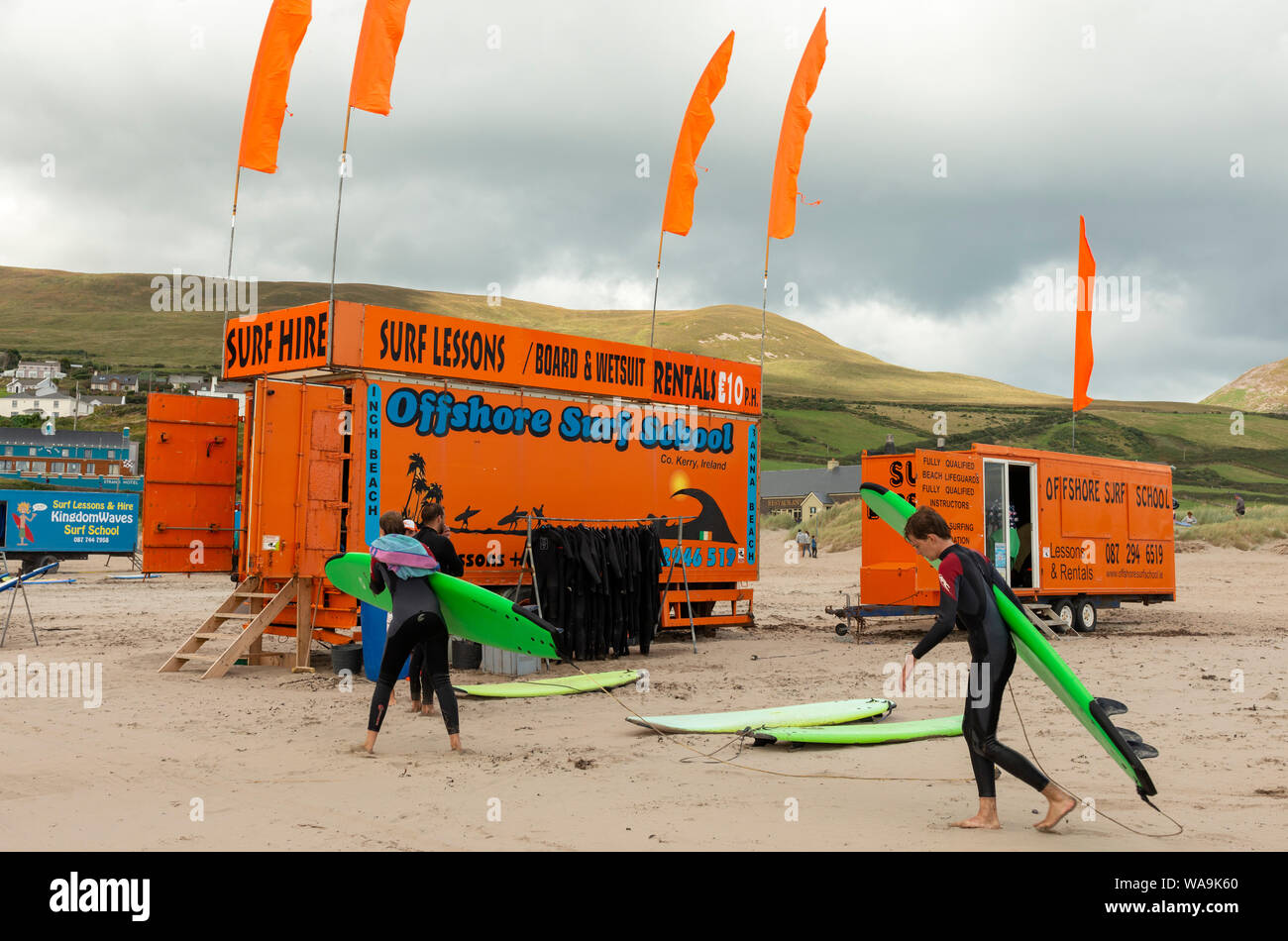 Young surfers at the Offshore Surf School surf hire orange cabin as surfing in Ireland concept at Inch Beach, County Kerry, Ireland Stock Photo