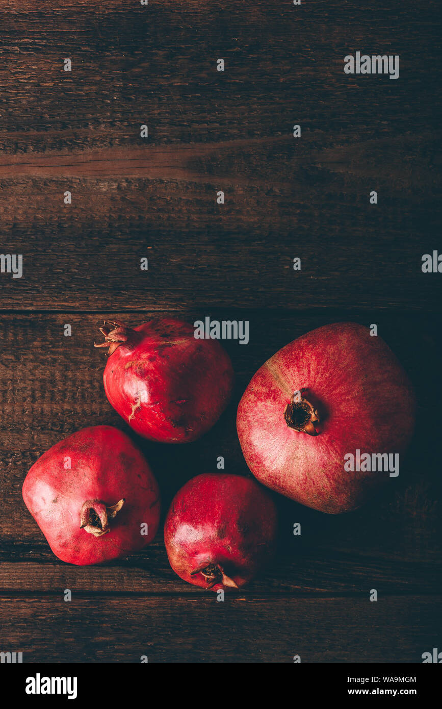 Four ripe pomegranate on rustic wooden table Stock Photo