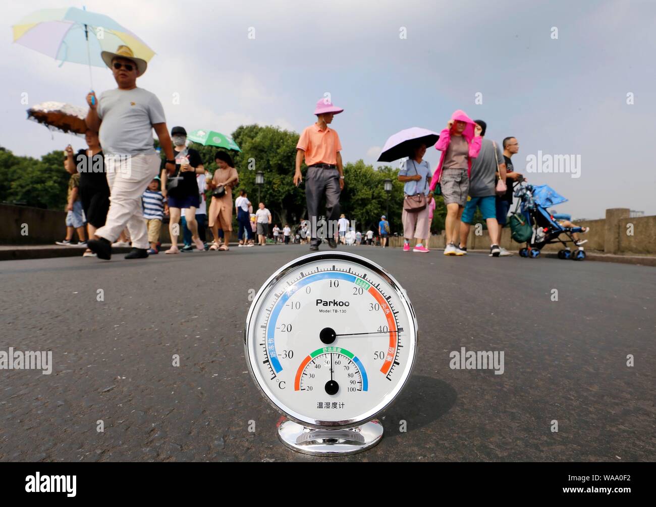 A local resident displays a thermometer showing the current temperature reaching 40 degrees Celsius on the West Lake scenic spot in Hangzhou city, eas Stock Photo