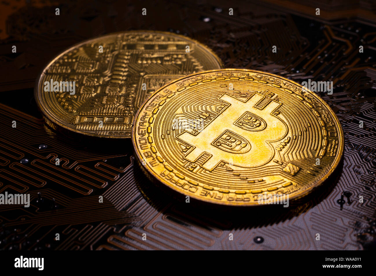 Virtual cryptocurrency money Bitcoin golden coins on a computer printed circuit board PCB. The future of money. Computational equipment. Dark image. Stock Photo