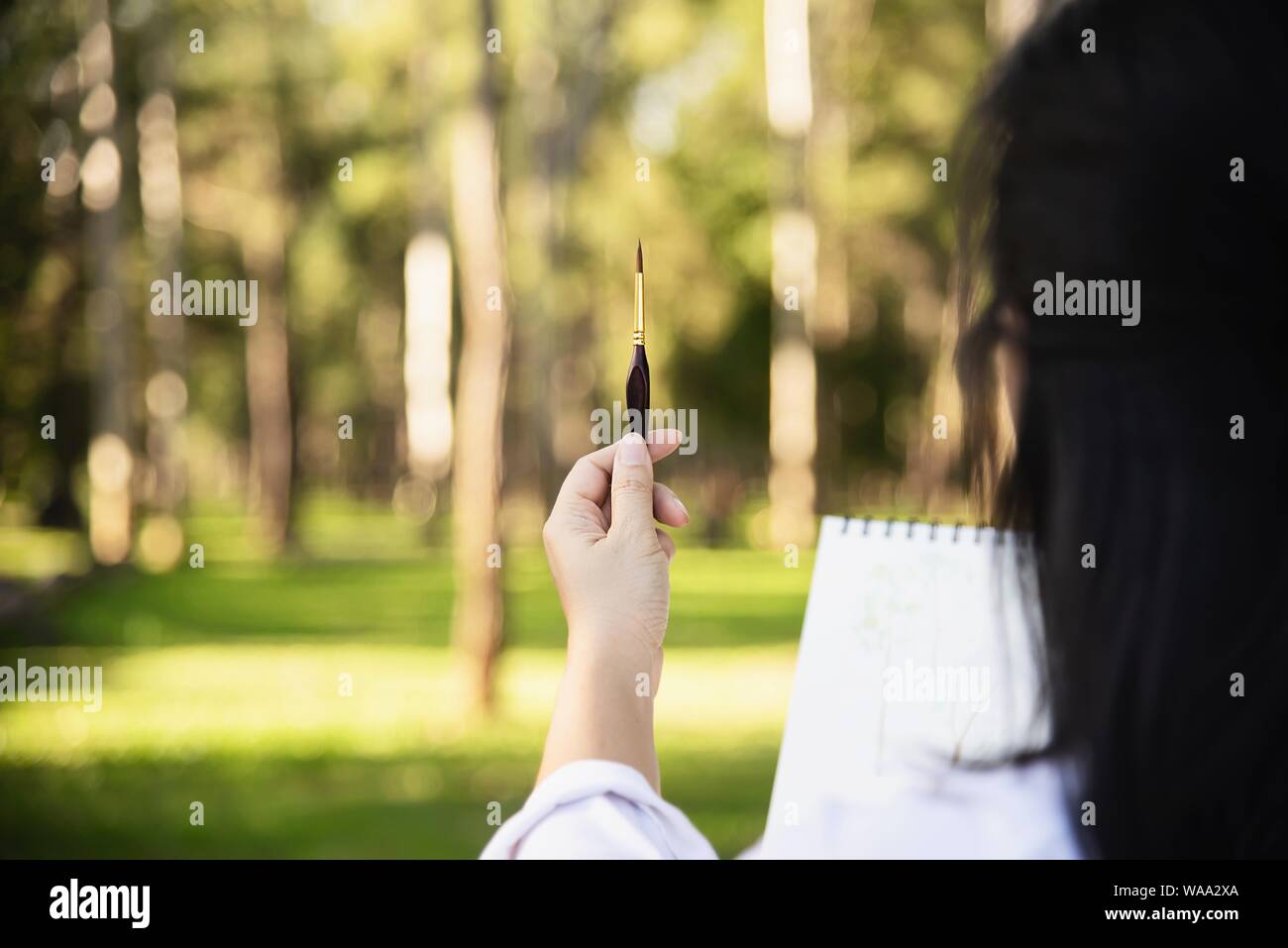 Relax woman painting water colour art work in green garden forest nature - people with creative art in nature stress reduction and meditation concept Stock Photo