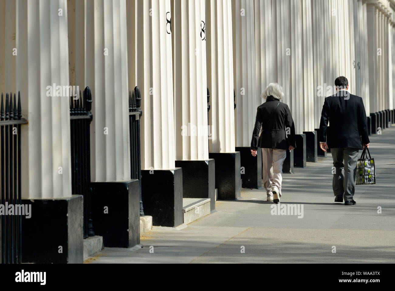 Couple walking past stucco columns, Eaton Square, garden square, Belgravia, West London, United Kingdom Stock Photo