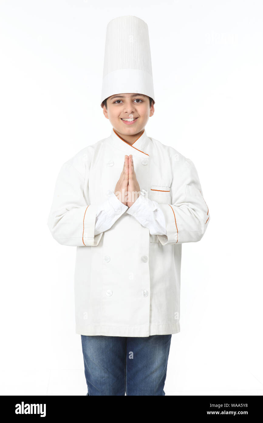 Boy pretending to be a chef and welcoming with hands joined Stock Photo