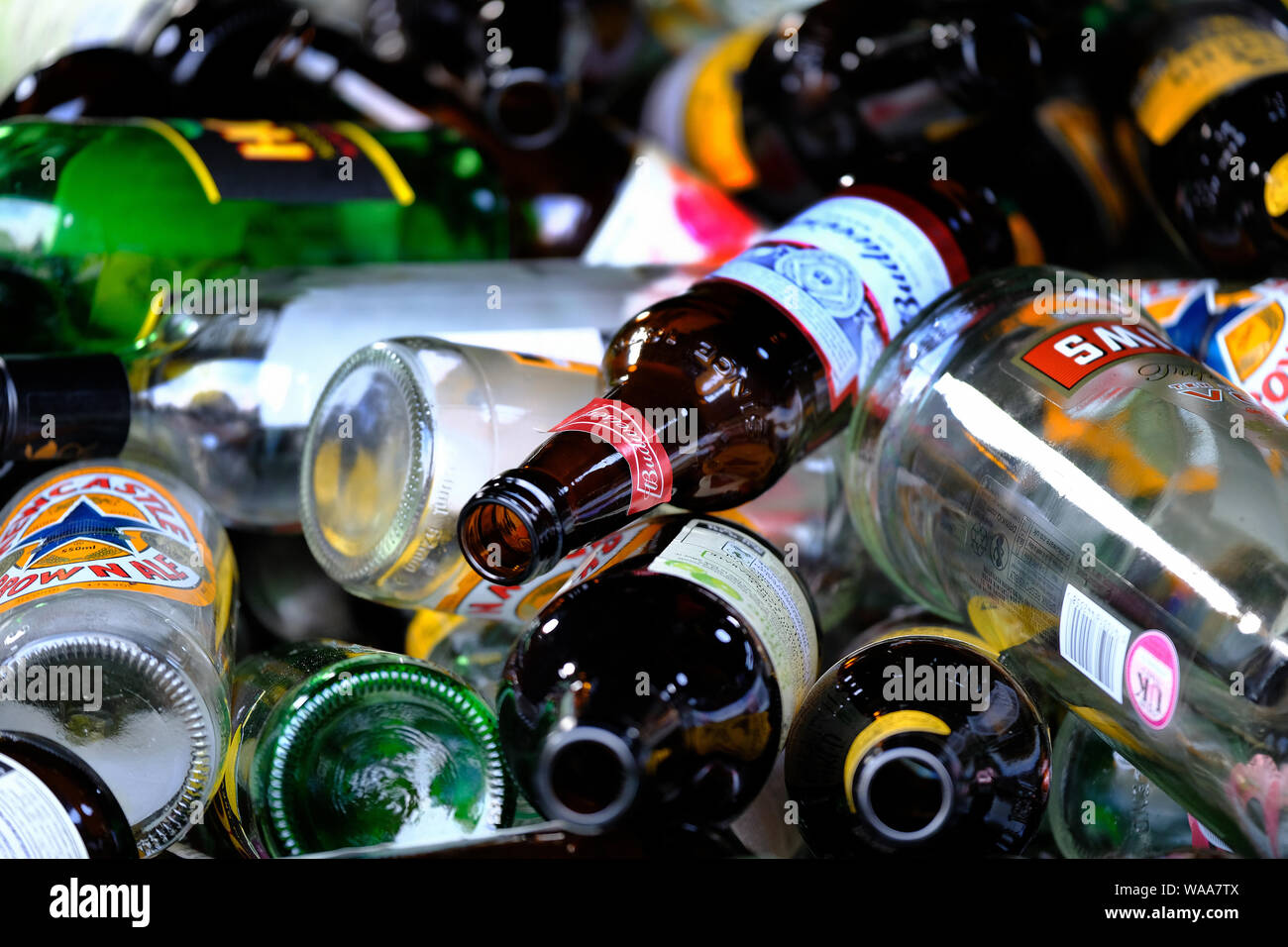 Large number of drink bottles in skip outside UK public house. Stock Photo