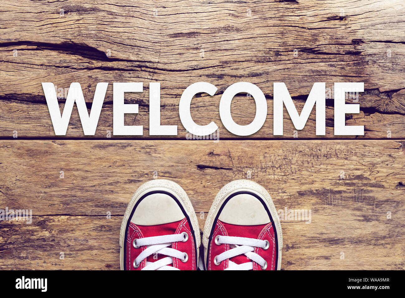 welcome sign text on wooden floor with red sneaker on it Stock Photo