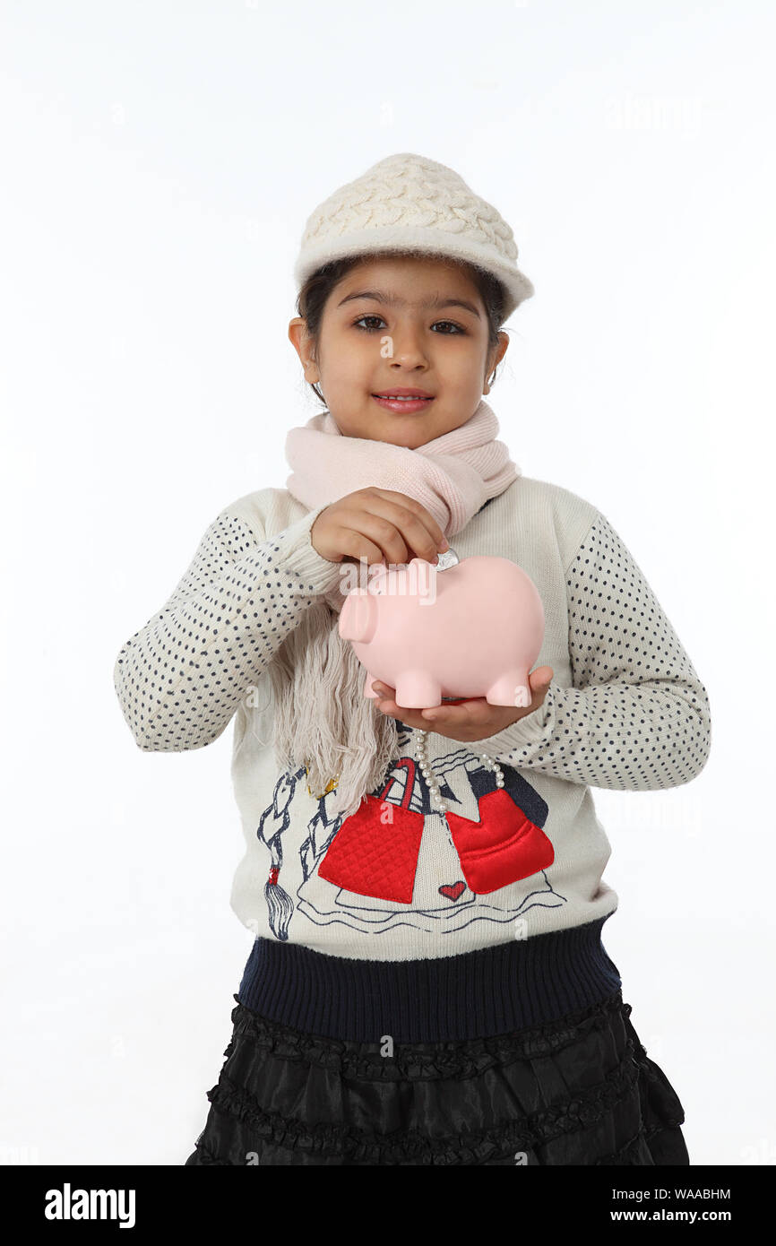 Girl putting a coin into a piggy bank Stock Photo - Alamy