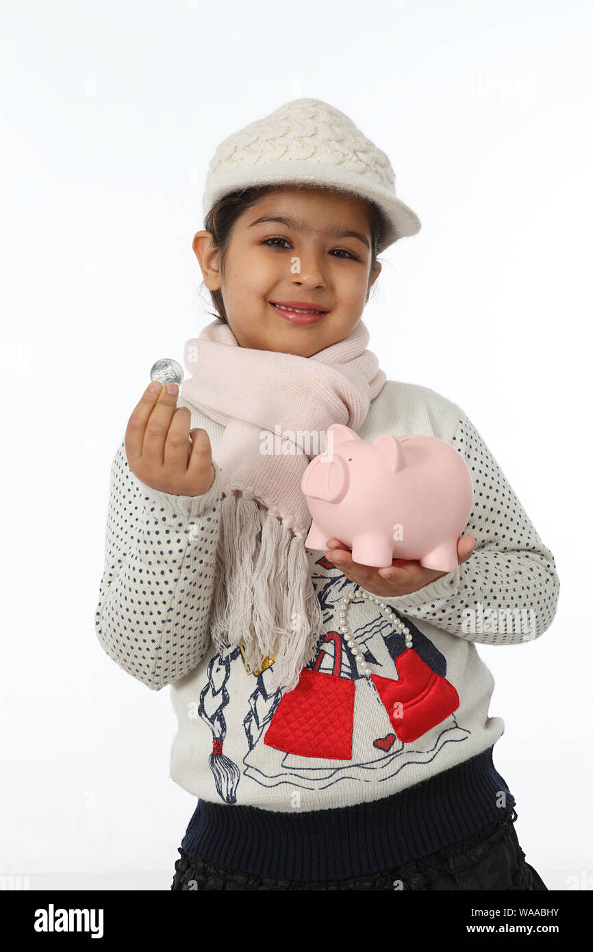 Girl showing a coin with a piggy bank Stock Photo - Alamy