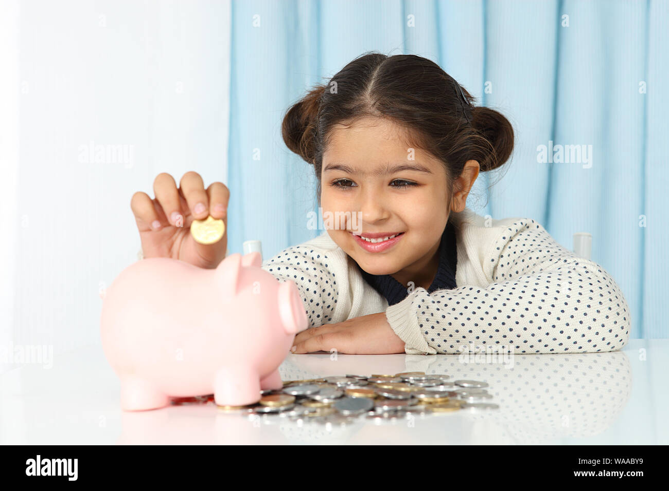 Girl inserting a coin into a piggy bank Stock Photo - Alamy