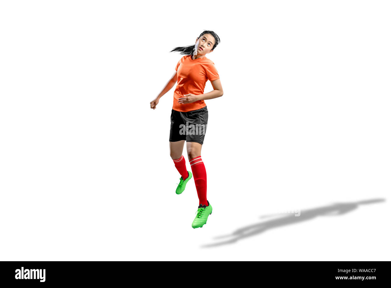 Asian football player woman jumps in the air and trying to heading the ball isolated over white background Stock Photo