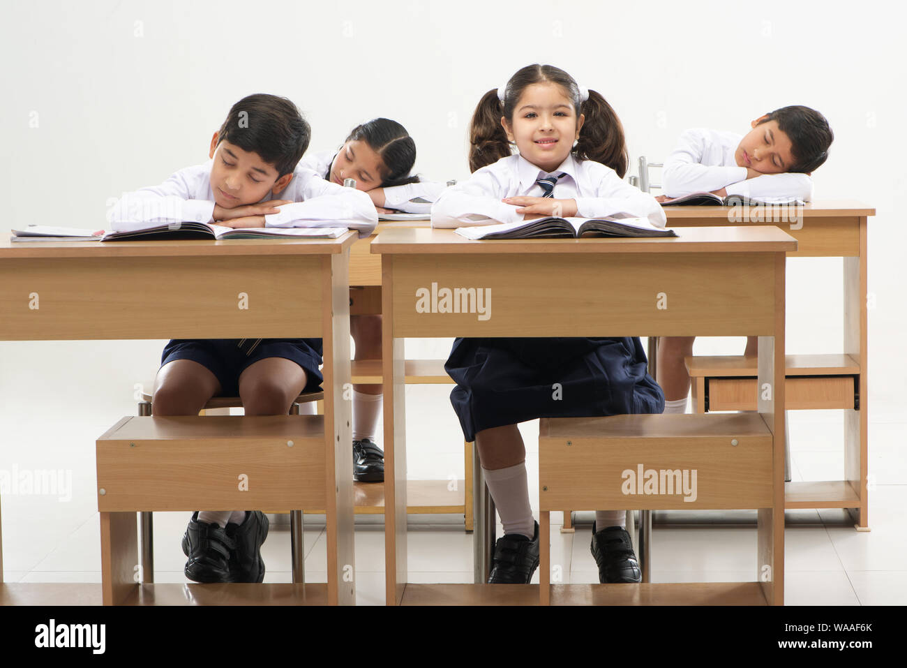 Sleeping students and diligent pupil in a school classroom Stock Photo