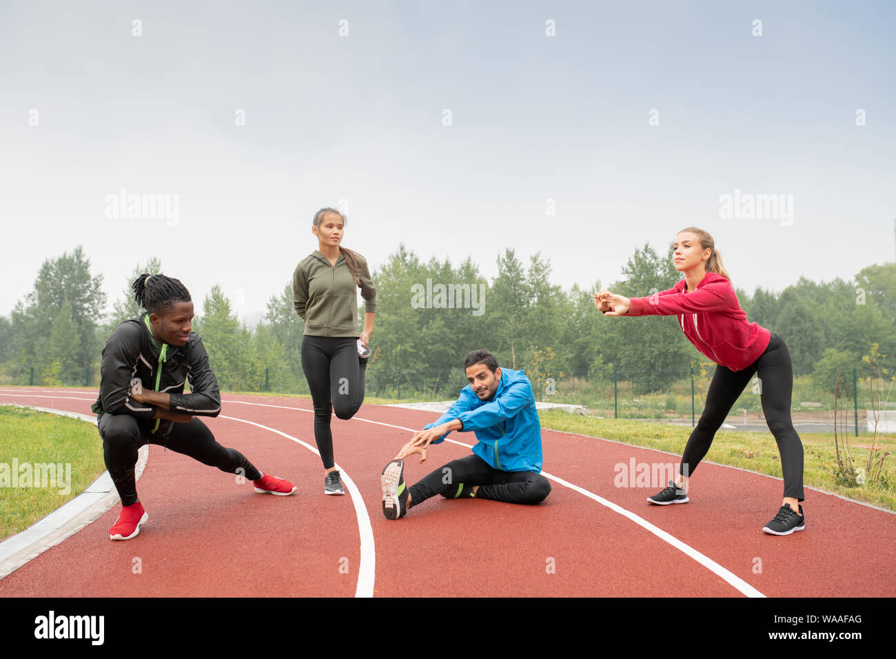 Young healthy intercultural men and women in sportswear doing physical exercises Stock Photo