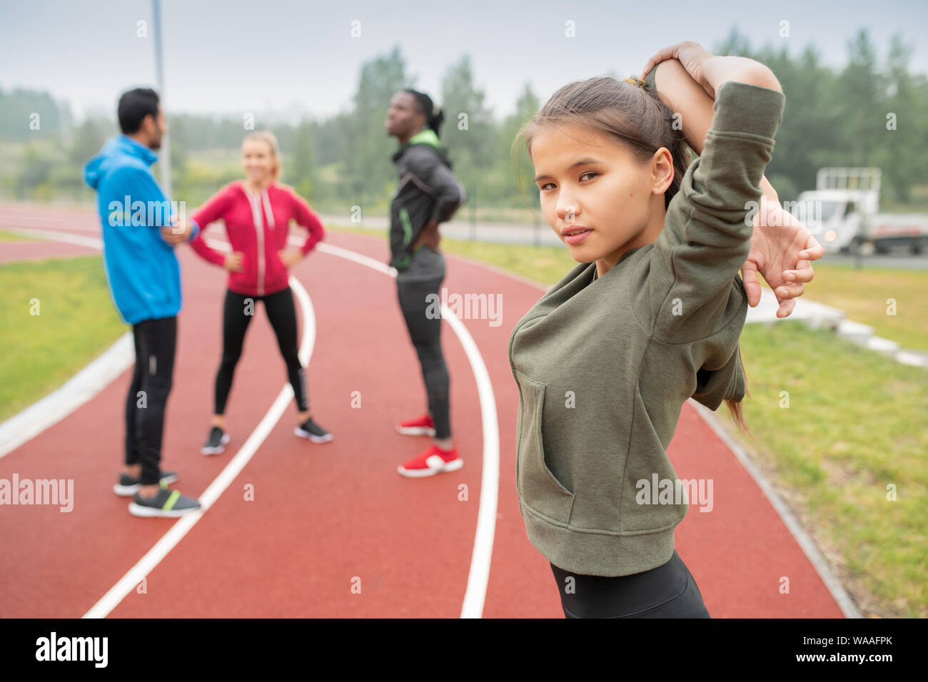 Sporty girl getting ready for marathon while doing warming up exercise Stock Photo
