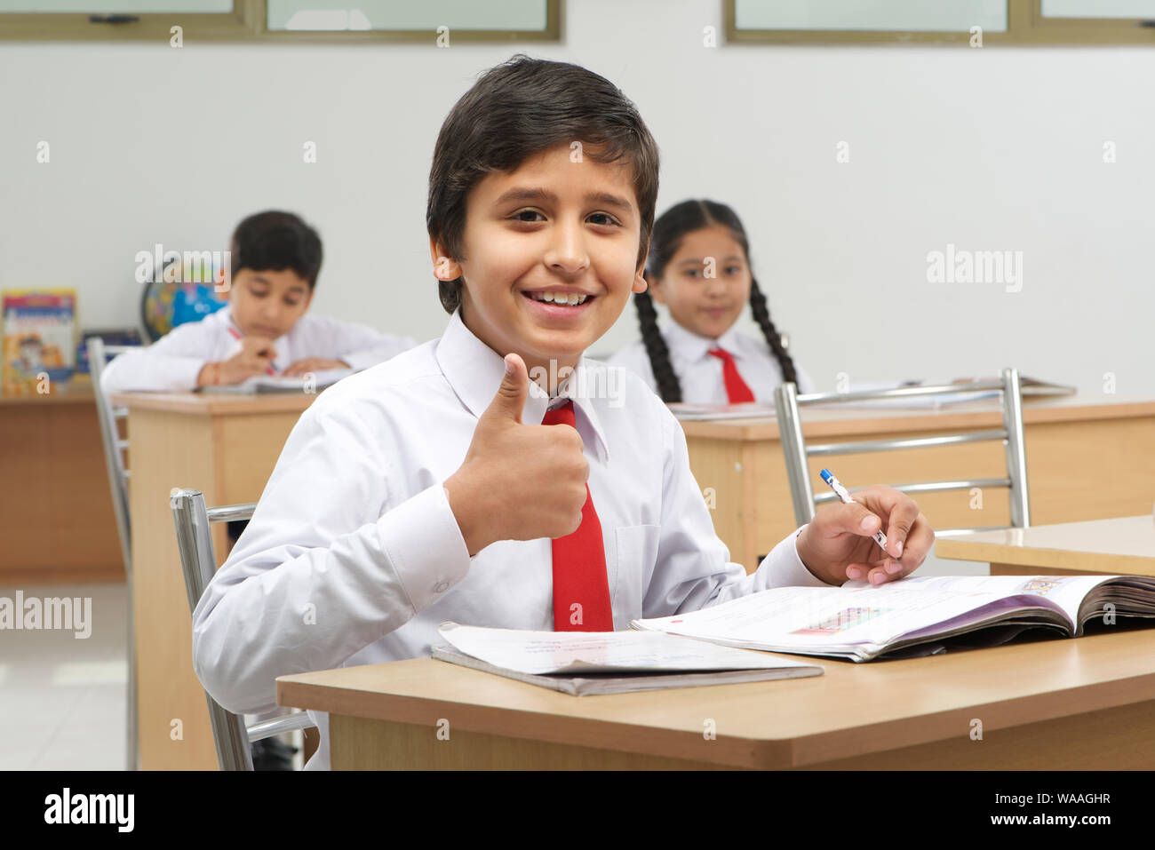 Schoolboy studying in a classroom and showing thumbs up sign Stock ...