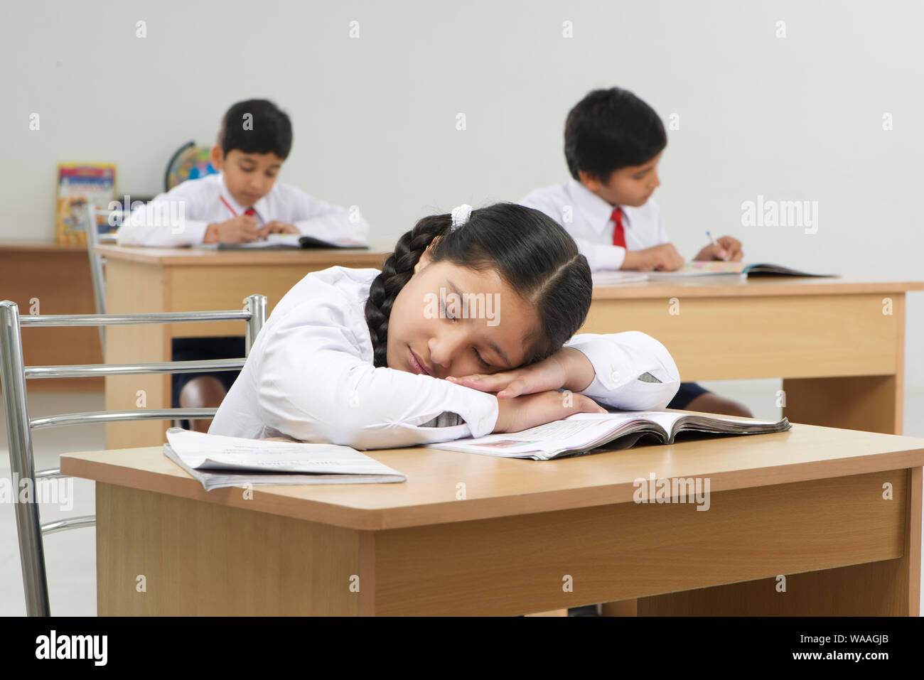Girl sleeping in classroom rest of students studying Stock Photo