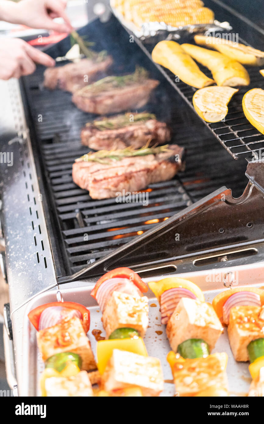 Grilling New York steak with a slice of butter and rosemary on an