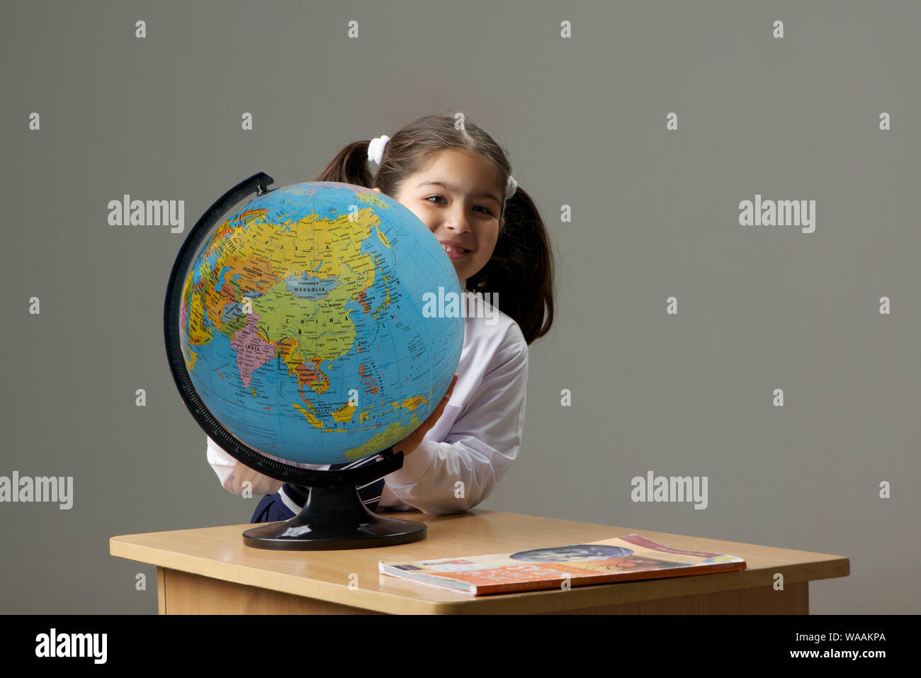 Schoolgirl holding a globe in classroom Stock Photo - Alamy