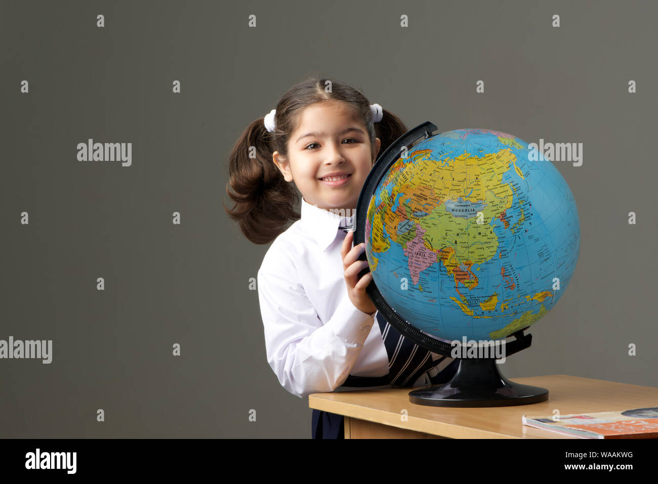 Schoolgirl holding a globe in classroom Stock Photo - Alamy