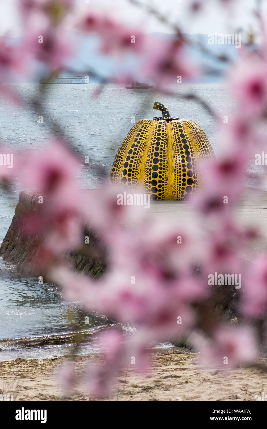 Cherry blossoms and the yellow pumpkin by Yayoi Kusama on Naoshima, Japan Stock Photo