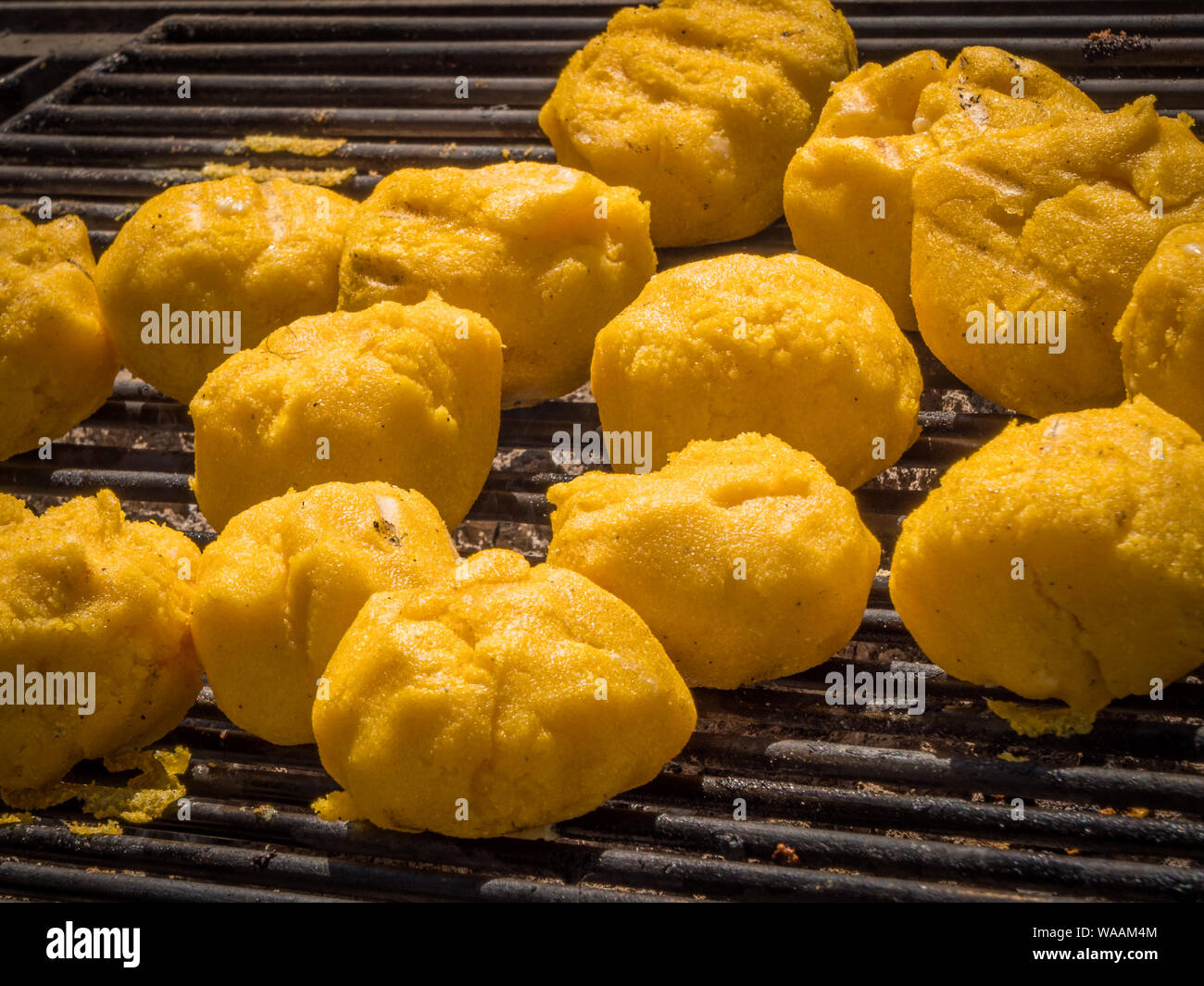 Roasting mămăligă and cheese ( Bulz ) on Grill Stock Photo