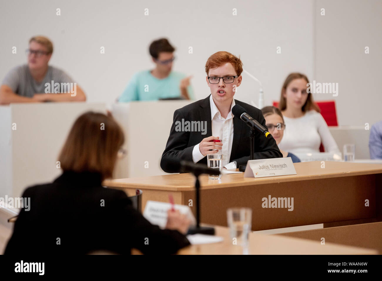19 August 2019, Brandenburg, Potsdam: Julius Niewisch, student at Humboldt-Gymnasium Potsdam, speaks at the event 'Jugend debattiert mit Spitzenkandidaten' ('Youth debates with top candidates') at the state election Brandenburg in the plenary hall of the state parliament from Brandenburg to Ursula Nonnemacher (l, from behind), top candidate of Bündnis 90/Die Grünen Brandenburg for the state election. At the event, which will take place within the framework of the 2019 junior elections, the top candidates of the five parties represented in the Brandenburg state parliament in parliamentary group Stock Photo