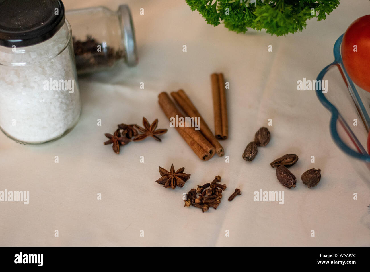 Cinnamon sticks, star anise, clove and cardamom, along with jars with