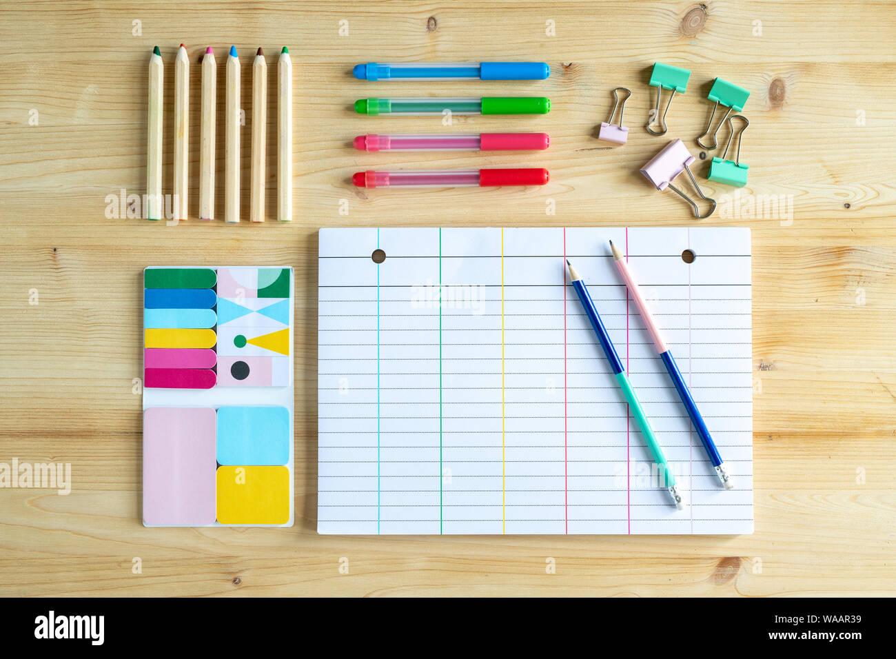 Page of notebook with two pencils and clips, sets of crayons and