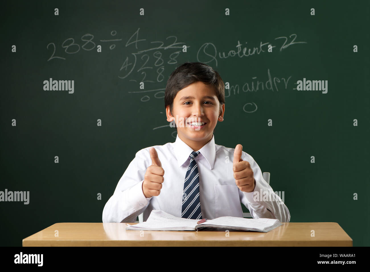 Schoolboy studying in a classroom and showing thumbs up sign Stock ...