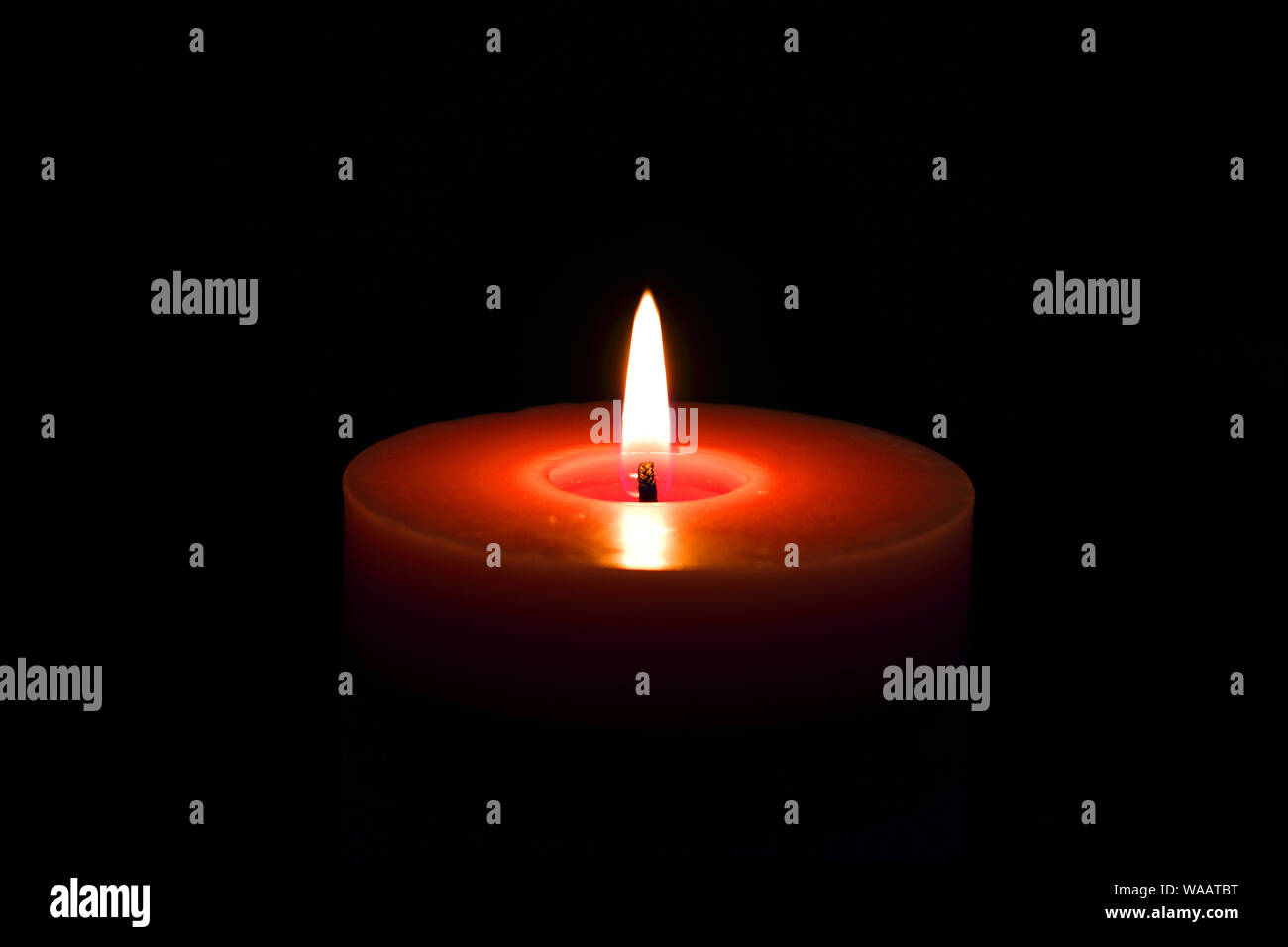 A single candle red flame isolated on black with selective focus Stock Photo