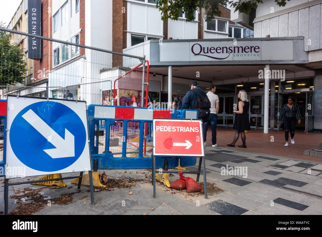 Maintenance works in the road in front of an entrance to The Queensmere shopping centre on High Street, Slough, UK Stock Photo